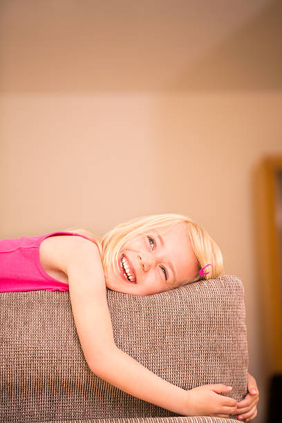 istock Girl lying on back of sofa looking at copy space 453571827