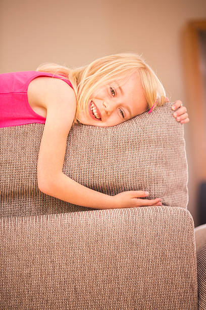 istock Little girl lying on back of sofa 453571833