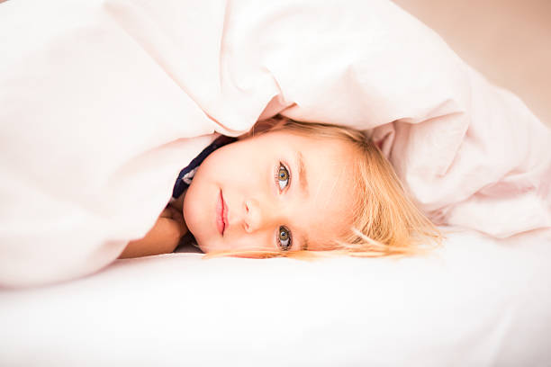 Cute girl in bed with a serious facial expression