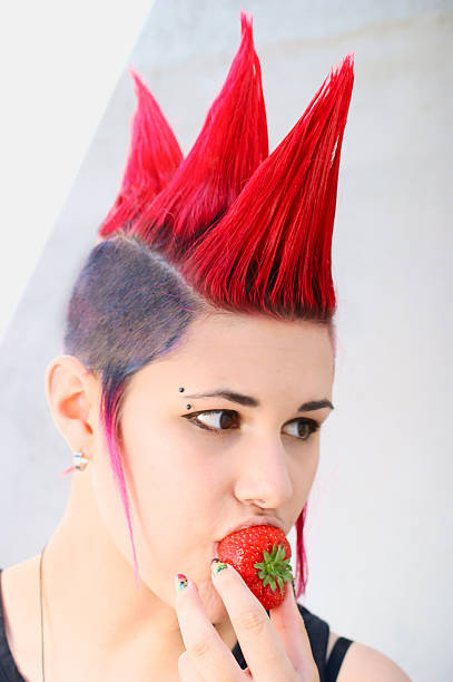 punk-mädchen isst erdbeere - frisur irokese stock-fotos und bilder