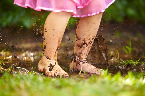 Cropped view of a little girl splashing in the mud