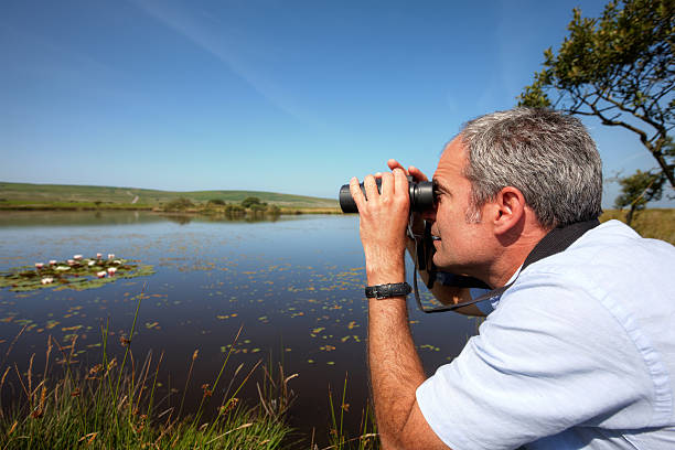 istock Mature caucasian man  through binoculars at lily pond 453588685