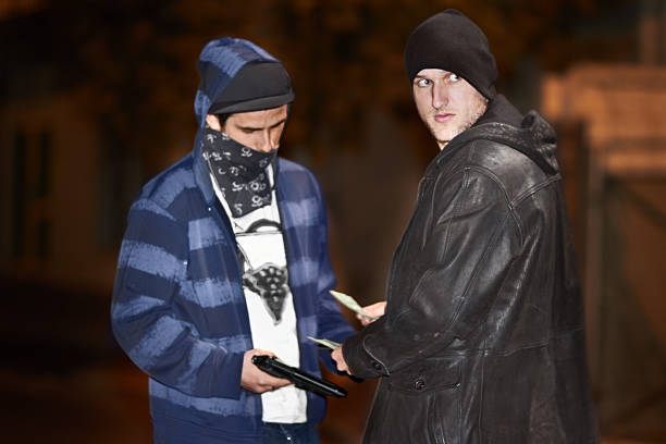 Underworld dealings Two criminal doing a shady deal while wielding a gun man holding gun at night in the city stock pictures, royalty-free photos & images