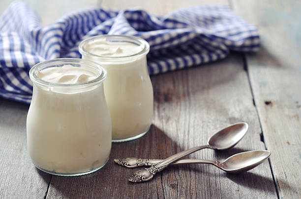 Greek yogurt in a glass jars Greek yogurt in a glass jars with spoons on wooden background YOGURT stock pictures, royalty-free photos & images