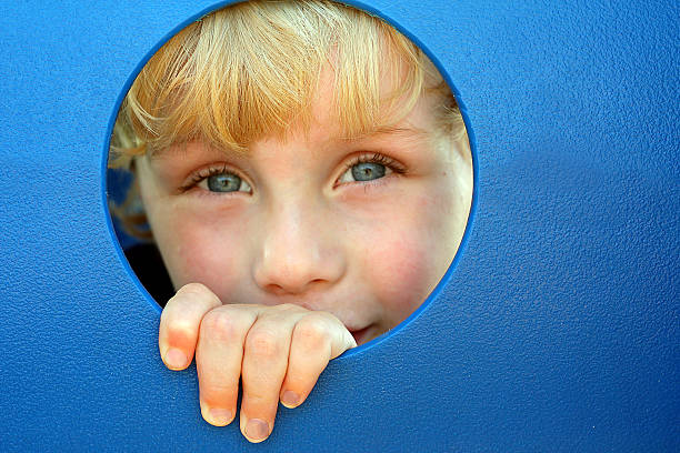 istock Child Peeking Through Hole at Playground 453610825