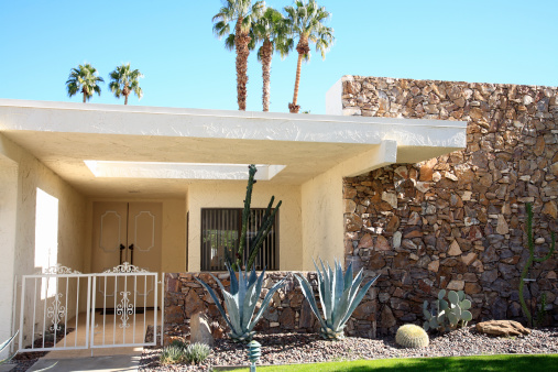 Front entrance and exterior view of mid century architecture. A main feature is the stone on the one wall.  Xeriscaped garden of cactus and succulents.