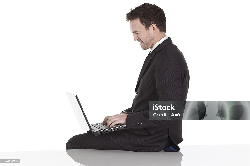 Vista lateral de un hombre de negocios utilizando el ordenador portátil - Foto de stock de 20 a 29 años libre de derechos