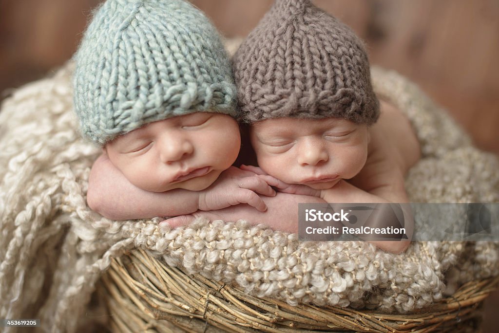 Newborn twins wearing tricot hats and sleeping in a basket A close up of newborn twins sleeping in a basket. Twin Stock Photo