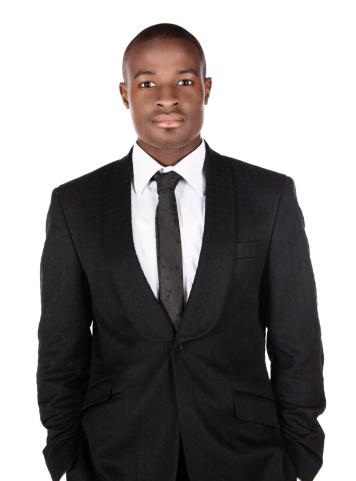Handsome young successful african businessman wearing a formal black suit, tie and white shirt. The man is standing and looking at the camera.