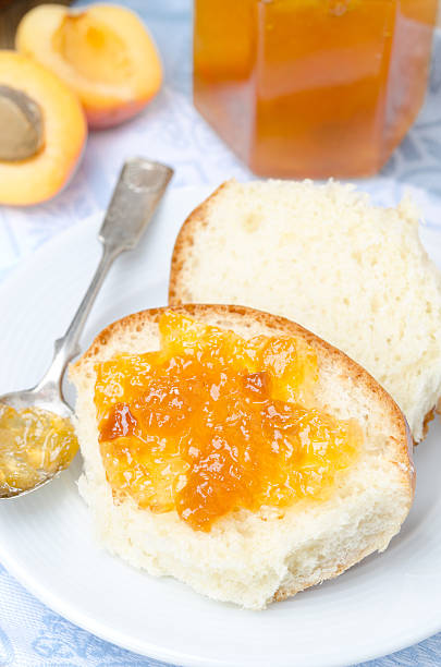 istock Sweet bun with apricot jam on the plate, vertical 453660355
