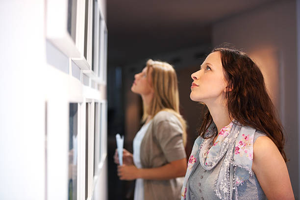 Closely examining the elements of a painting Two female friends viewing paintings while attending an exhibition museum photos stock pictures, royalty-free photos & images