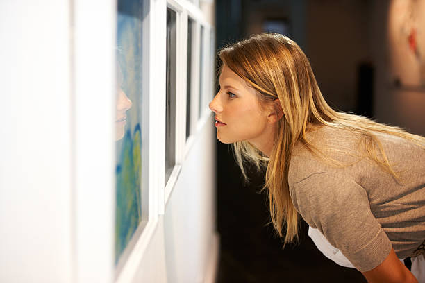 Getting a closer look at the elements A young woman leaning over and closely examining a painting fine art painting photos stock pictures, royalty-free photos & images