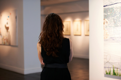 A rearview shot of a young woman looking into the foyer of a gallery