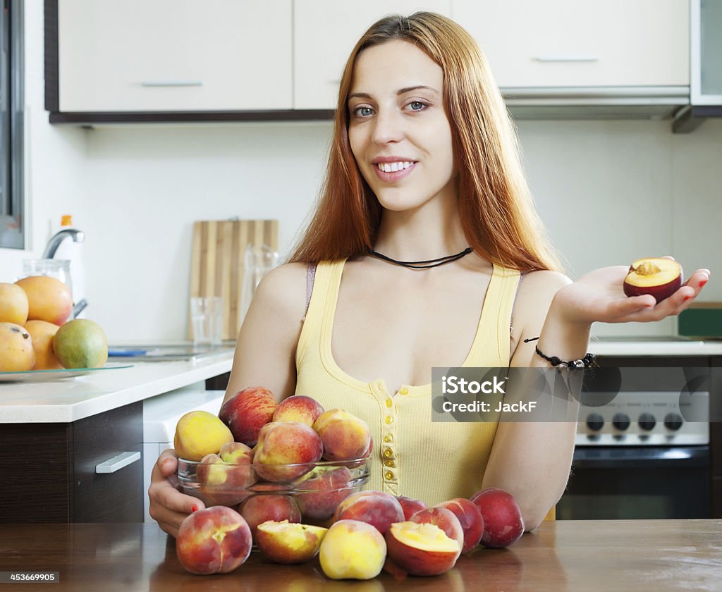 Mulher segurando pêssegos à mesa em casa - Foto de stock de 20 Anos royalty-free