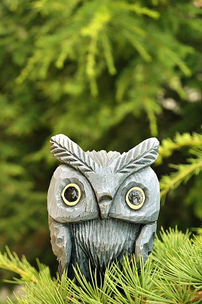 istock wooden owl statue on pine tree branch 453679891