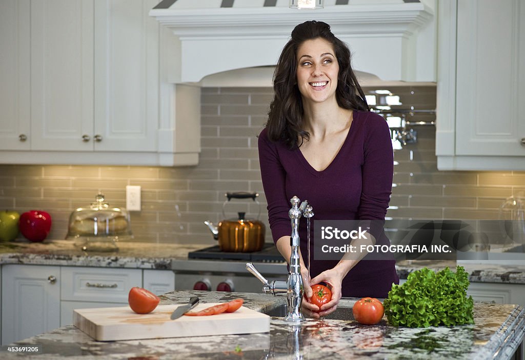 Young woman in the kitchen Young Caucasian woman preparing food in her new new luxury kitchen. Adult Stock Photo