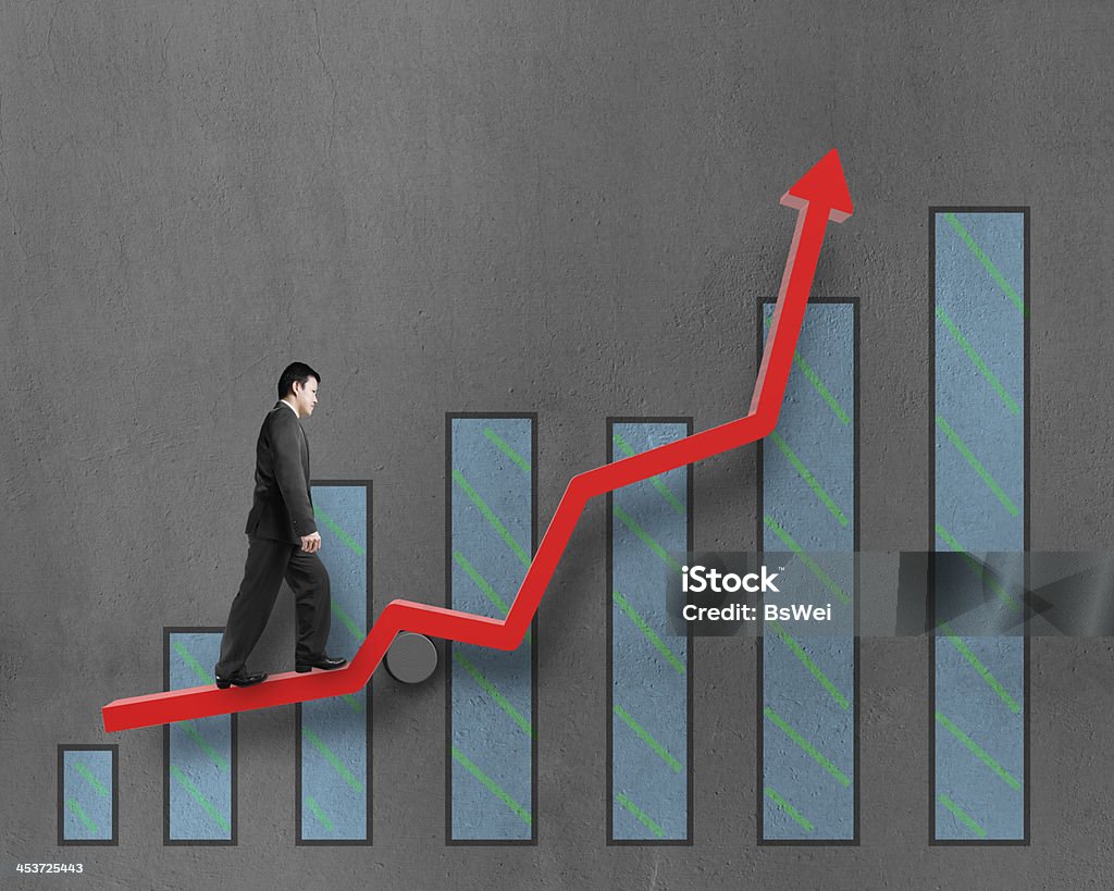 Businessman walking on growth red arrow with chart Businessman walking on growth red arrow with chart in concrete wall background Achievement Stock Photo