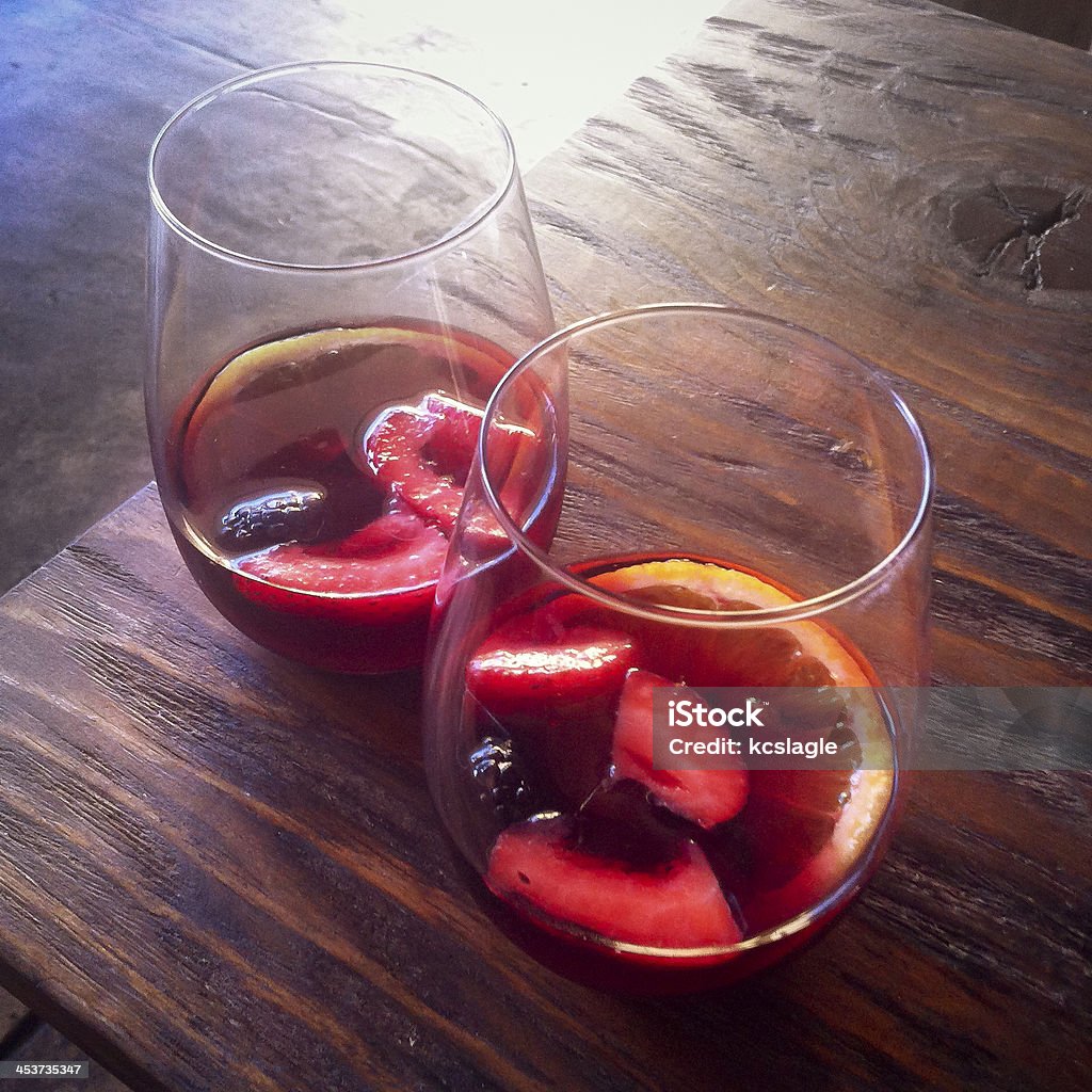 Two Glasses of Red Sangria on a Wood Table Two glasses of red sangria sitting on a wood table with beautiful backlight. Red Wine Stock Photo