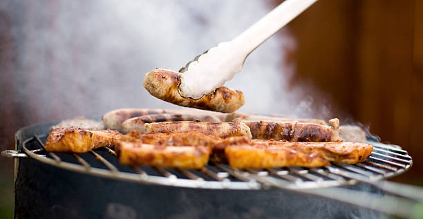 BBQ on a summers weekend Grilling at summer weekend. Fresh juicy  sausages and chicken serving tongs stock pictures, royalty-free photos & images