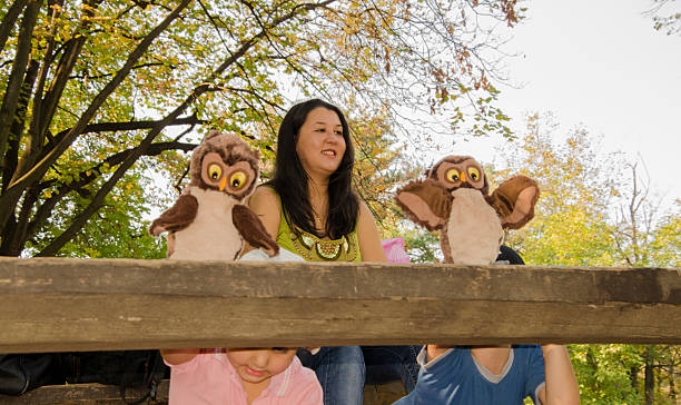 Two children performing puppet show in a park, on a bench as a stage.