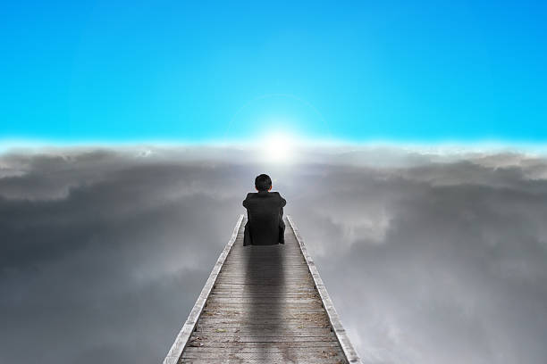 istock businessman sitting on pier looking sunrise with clouds, blue sky 453748273