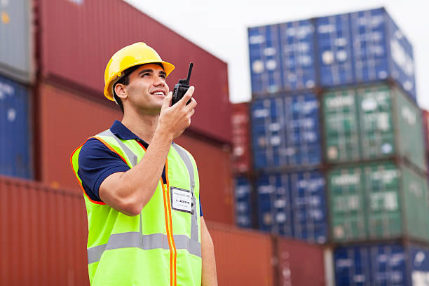 harbor worker talking on the walkie-talkie young harbor worker talking on the walkie-talkie at container warehouse walkie talkie photos stock pictures, royalty-free photos & images
