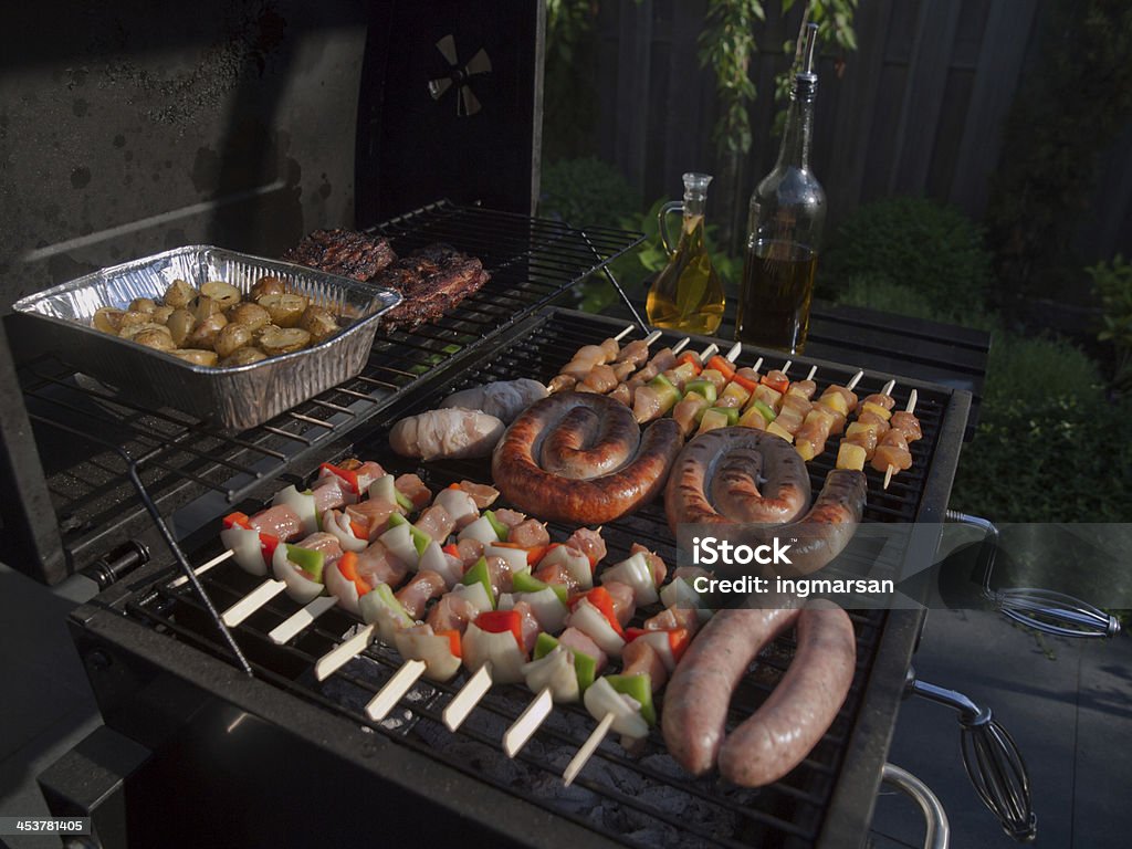 Grill food Grilling food on the BBQ on a summer day in the garden, boerewors, skewers, shashliks, sausages, herbs and vegetables Barbecue - Meal Stock Photo