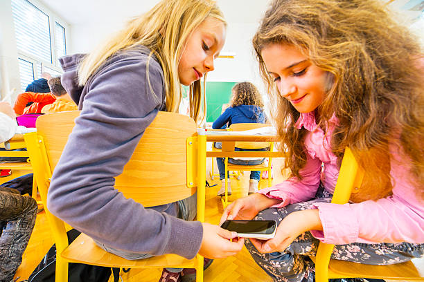 istock Primary school students cheating in classroom with smartphone 453781869