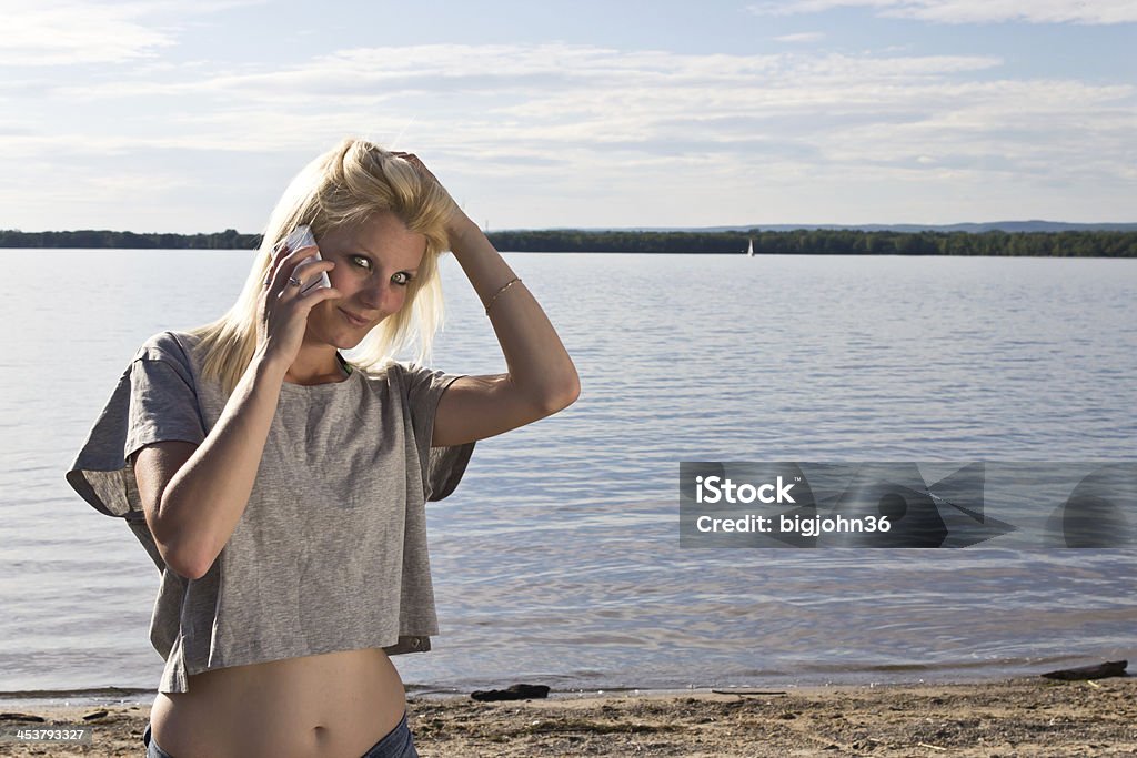 Young woman talking on smart phone Young woman talking on smart phone on the beach Crop Top Stock Photo