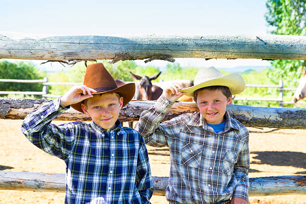 istock Two Young Cowboys Leaning On A Log Fence 453793573