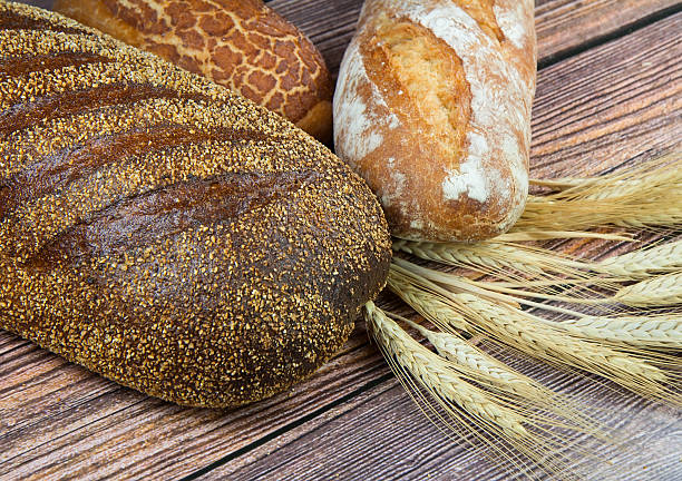 istock Assorted bread and wheat ears on wooden background 453800481