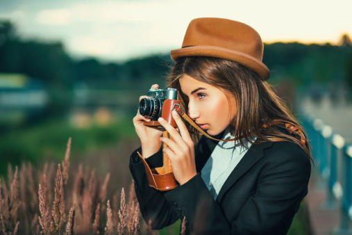 Beautiful hipster girl shooting with retro camera