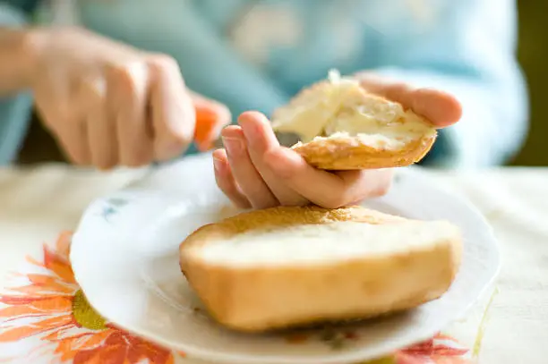 Breakfast close-up with hands, bread and butter