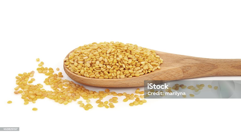 Mung Dahl Mung dahl dried food ingredient in a wooden spoon over white background. Bean Stock Photo