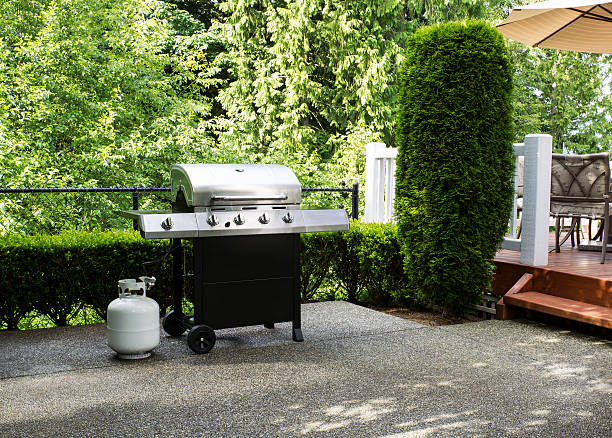 Outdoor cooker on House Patio Horizontal photo of a large barbeque cooker on concrete outdoor patio with woods and deck in background propane photos stock pictures, royalty-free photos & images