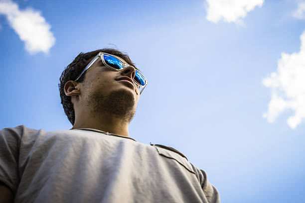 istock Young man wearing sunglasses with cloudy sky background 453836501