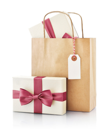 Brown paper bag with gift and paper tag isolated on a white background