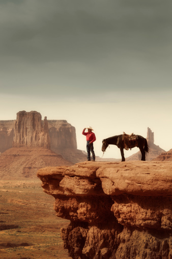 Subject: A native American Indian cowboy on a horse over a cliff looking into the distance.