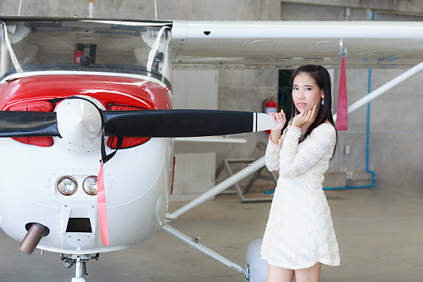 An African American woman takes a selfie with her young Hispanic friend in front of a private jet.