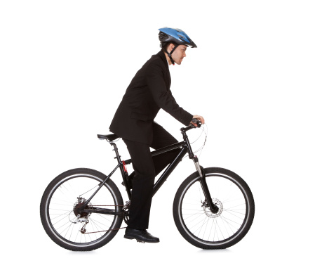 Businessman riding a bicycle to work in his suit exercising for fitness and health and to save on carbon emissions