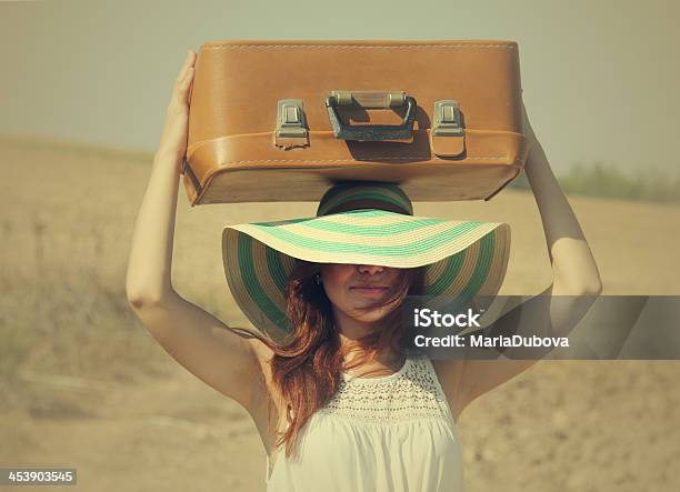 Young Woman In A Sun Hat Holding Luggage On Her Head Stock Photo - Download Image Now