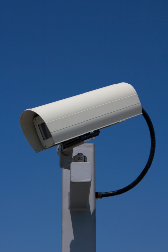 Close-up of modern outdoor surveillance camera facing left.