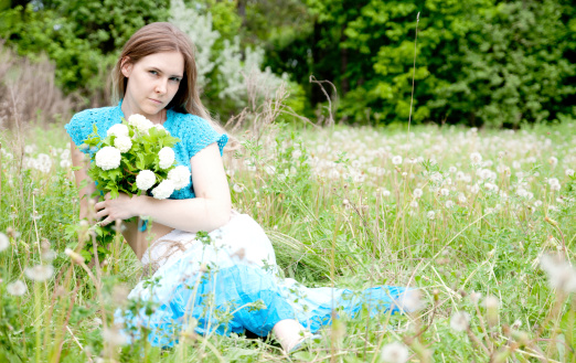 Ukrainian Fashion girl sitting in a field with flowers, a field with dandelions
