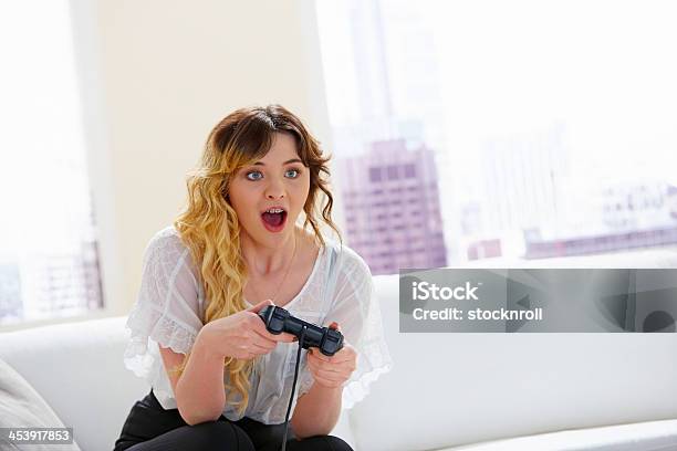 Pretty Young Lady Sitting On Couch Playing Exciting Video Game Stock Photo - Download Image Now