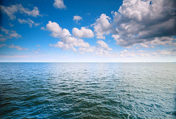 istock Cloudy blue sky above a surface of the sea 453926403