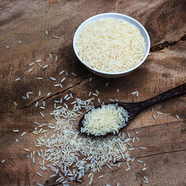 istock Rice with wooden spoon and white cup on wood table. 453935459