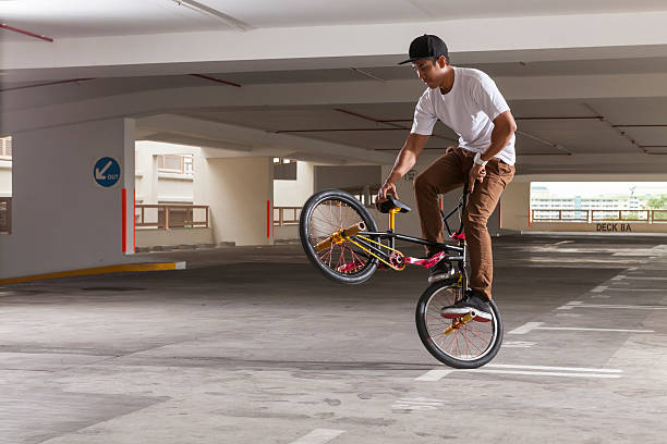 BMX Bicycle rider doing his stunt BMX Bicycle rider doing his stunt in a multistorey carpark. bicycle stunts stock pictures, royalty-free photos & images