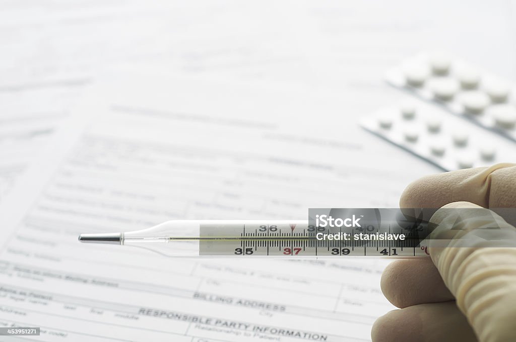 Thermometer in hand on patient registration form Accuracy Stock Photo