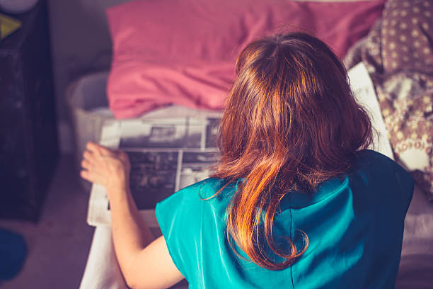 istock Woman lying on bed is reading a newspaper 453952705