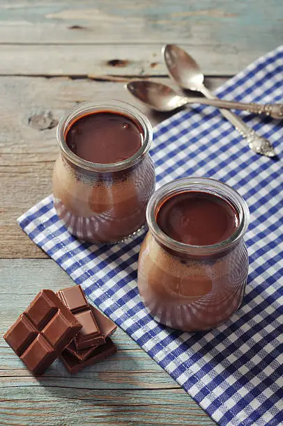 Chocolate dessert panna cotta in glass jars on wooden background